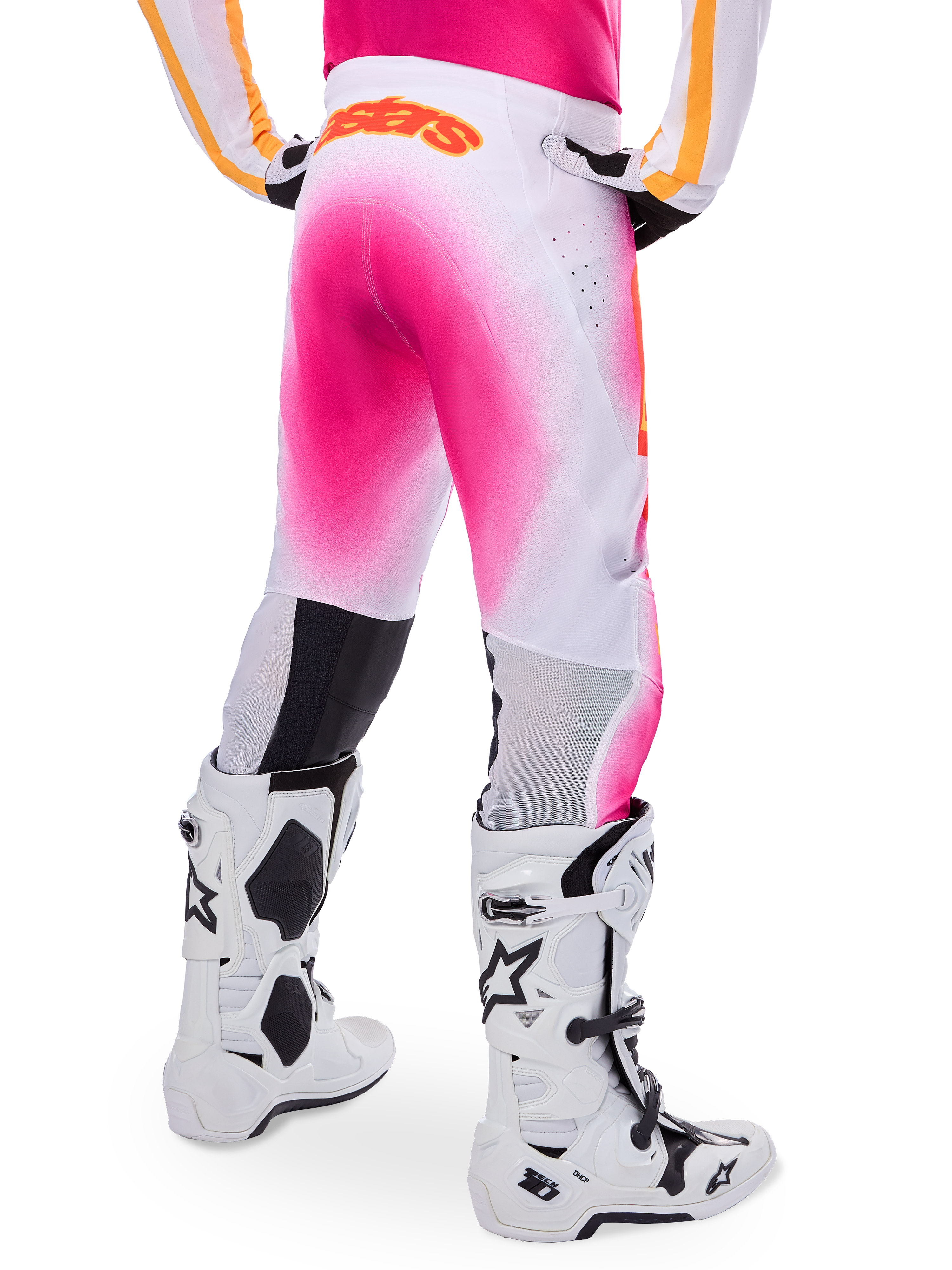Alpinestars Supertech AFD MIG Limited Edition Motocross Pants, Pink and White, rear view featuring a vibrant pink gradient spray effect, orange logo on the back waist, paired with white and black Tech 10 boots, professional off-road racing apparel