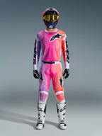 Zawodnik motocrossowy w koszulce 2026 Racer Air Portl i pasujących spodniach, różowy, fioletowy i pomarańczowy gradient z czarnym logo Alpinestars, białe buty wyścigowe, czarne rękawice i wielokolorowy kask, profesjonalny strój do wyścigów off-road