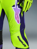 Alpinestars 2026 Supertech Vista Pants, spodnie motocrossowe, żółte, fioletowe i czarne, zbliżenie na logo gwiazdy z gradientem i laserowo wycinane otwory wentylacyjne, w zestawie z pasującymi rękawicami wyścigowymi