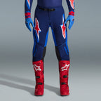 Zestaw Alpinestars 2026 Supertech Vista, spodnie motocrossowe w kolorze granatowym i jasnoniebieskim z czerwonymi i białymi logotypami, jasnoniebieskie rękawice i jaskrawoczerwone buty motocrossowe, profesjonalna odzież wyścigowa
