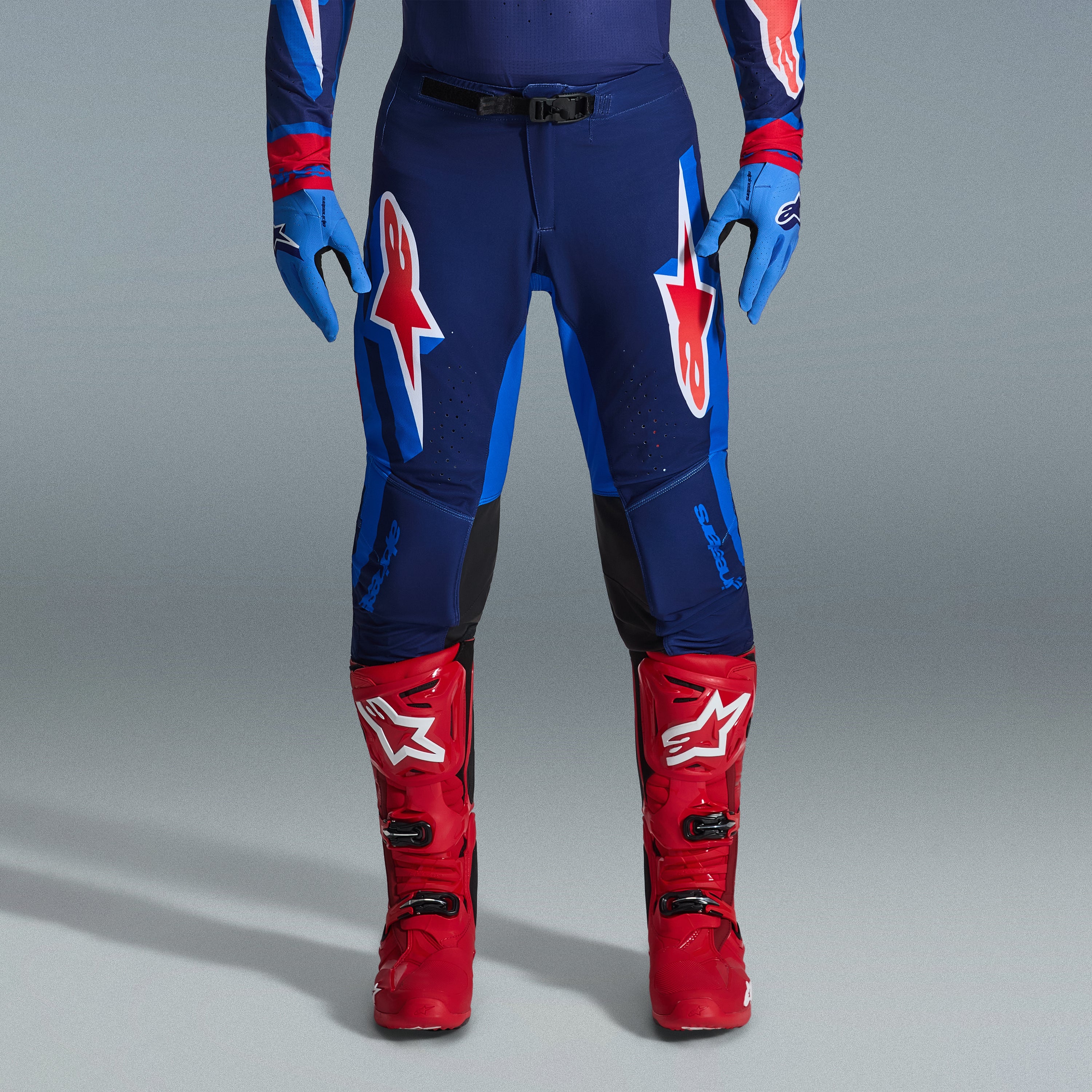 Zestaw Alpinestars 2026 Supertech Vista, spodnie motocrossowe w kolorze granatowym i jasnoniebieskim z czerwonymi i białymi logotypami, jasnoniebieskie rękawice i jaskrawoczerwone buty motocrossowe, profesjonalna odzież wyścigowa