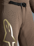 Alpinestars męskie spodnie Supertech Air Gold, brązowe ze złotym logo, klamra magnetyczna SX1 i perforacje.