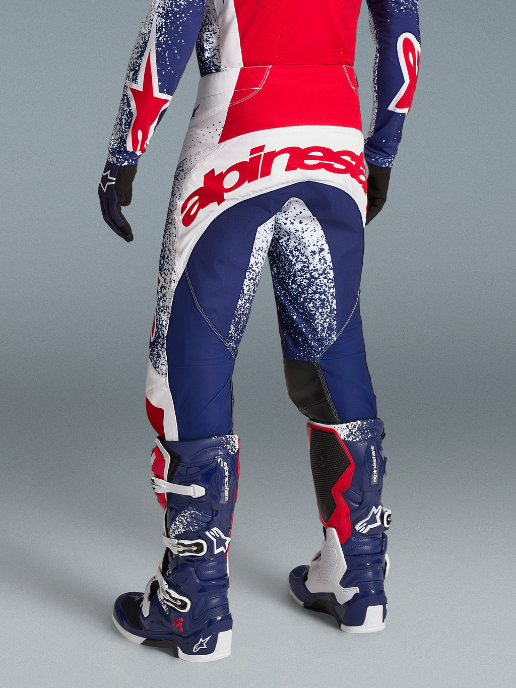 Alpinestars Techstar Unity, męskie spodnie motocrossowe, czerwone, białe i niebieskie, edycja limitowana, duże logo z tyłu.