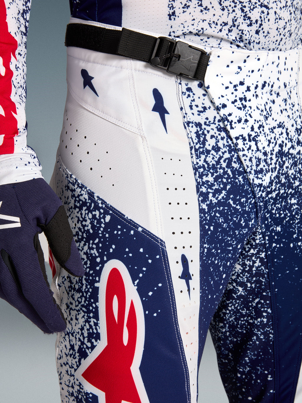 Alpinestars Techstar Unity, spodnie motocrossowe, białe, niebieskie i czerwone, klamra magnetyczna SX2, laserowe perforacje.