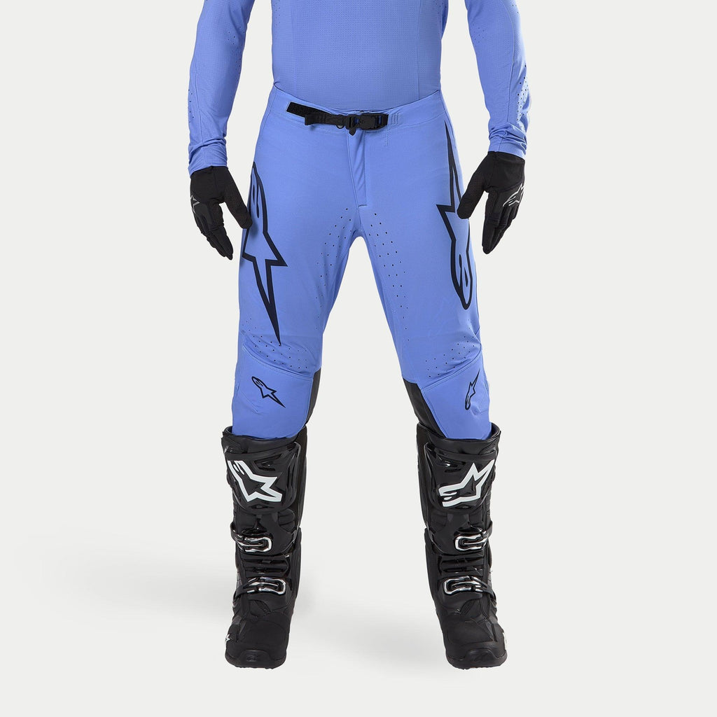 Alpinestars Supertech Dade Pants 2024, spodnie motocrossowe, jasnoniebieskie, z dużymi czarnymi logo Astars na udach i czarną klamrą w pasie, zestawione z czarnymi butami motocrossowymi i pasującą niebieską koszulką, profesjonalna odzież wyścigowa off-road