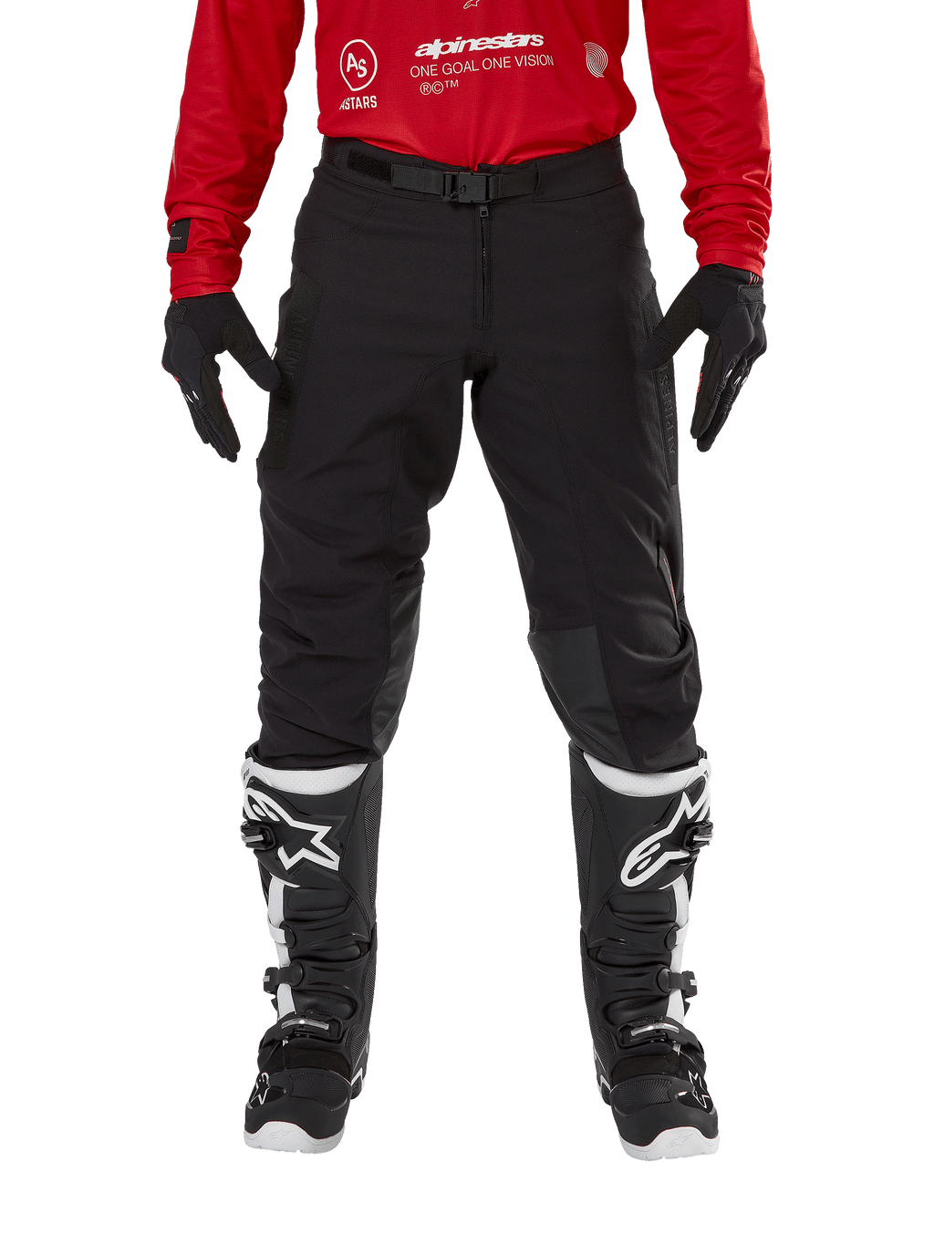 Alpinestars Techdura Pants, spodnie enduro i off-road, czarne, noszone z czerwoną bluzą Alpinestars i czarno-białymi butami, wytrzymała konstrukcja z rozciągliwego płótna, regulowana magnetyczna klamra paska, skórzane wzmocnienia na kolanach dla lepszej wydajności off-road