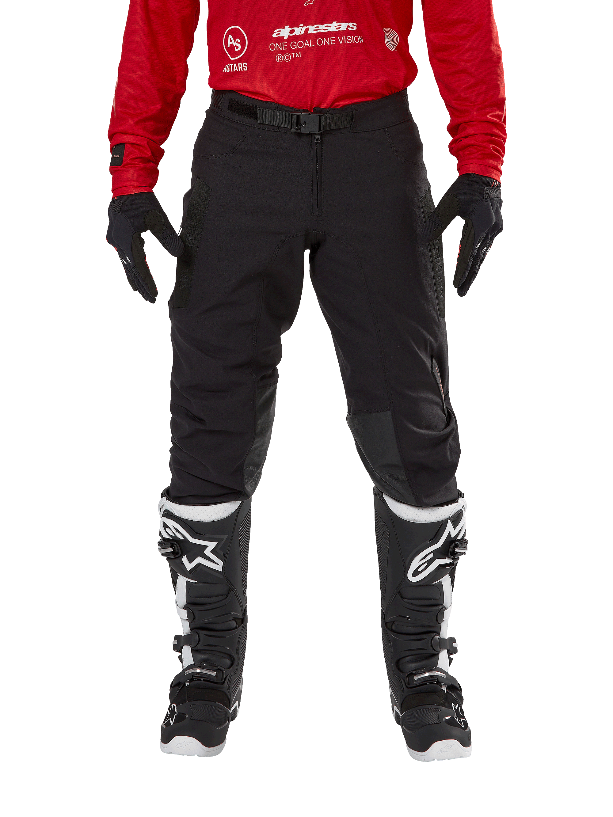 Alpinestars Techdura Pants, spodnie enduro i off-road, czarne, noszone z czerwoną bluzą Alpinestars i czarno-białymi butami, wytrzymała konstrukcja z rozciągliwego płótna, regulowana magnetyczna klamra paska, skórzane wzmocnienia na kolanach dla lepszej wydajności off-road