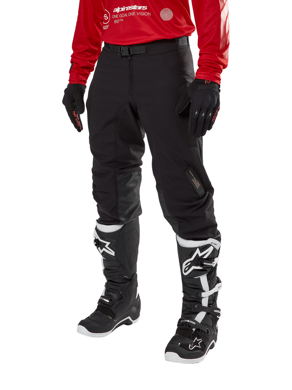 Alpinestars Techdura Pants, czarne spodnie motocyklowe off-road, zestawione z czerwoną bluzą z długim rękawem i czarno-białymi butami motocrossowymi, wytrzymała konstrukcja z elastycznego poliamidu, skórzane wzmocnienia wewnętrznej strony kolan, regulowany pasek z klamrą do jazdy enduro