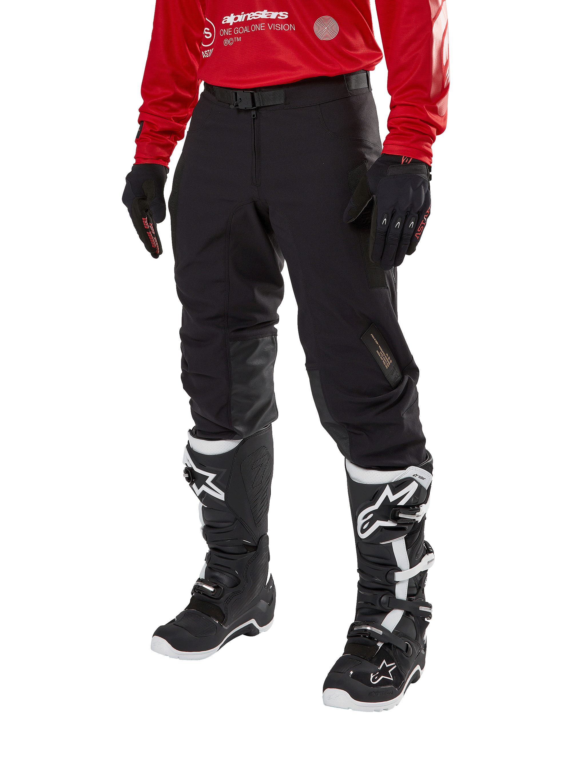 Alpinestars Techdura Pants, czarne spodnie motocyklowe off-road, zestawione z czerwoną bluzą z długim rękawem i czarno-białymi butami motocrossowymi, wytrzymała konstrukcja z elastycznego poliamidu, skórzane wzmocnienia wewnętrznej strony kolan, regulowany pasek z klamrą do jazdy enduro