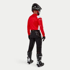Spodnie Alpinestars Techdura, spodnie enduro off-road, czarne, widok z tyłu na motocykliście w czerwono-białej bluzie i czarno-białych butach, z białym logo gwiazdy z tyłu oraz wytrzymałą, techniczną, rozciągliwą konstrukcją.