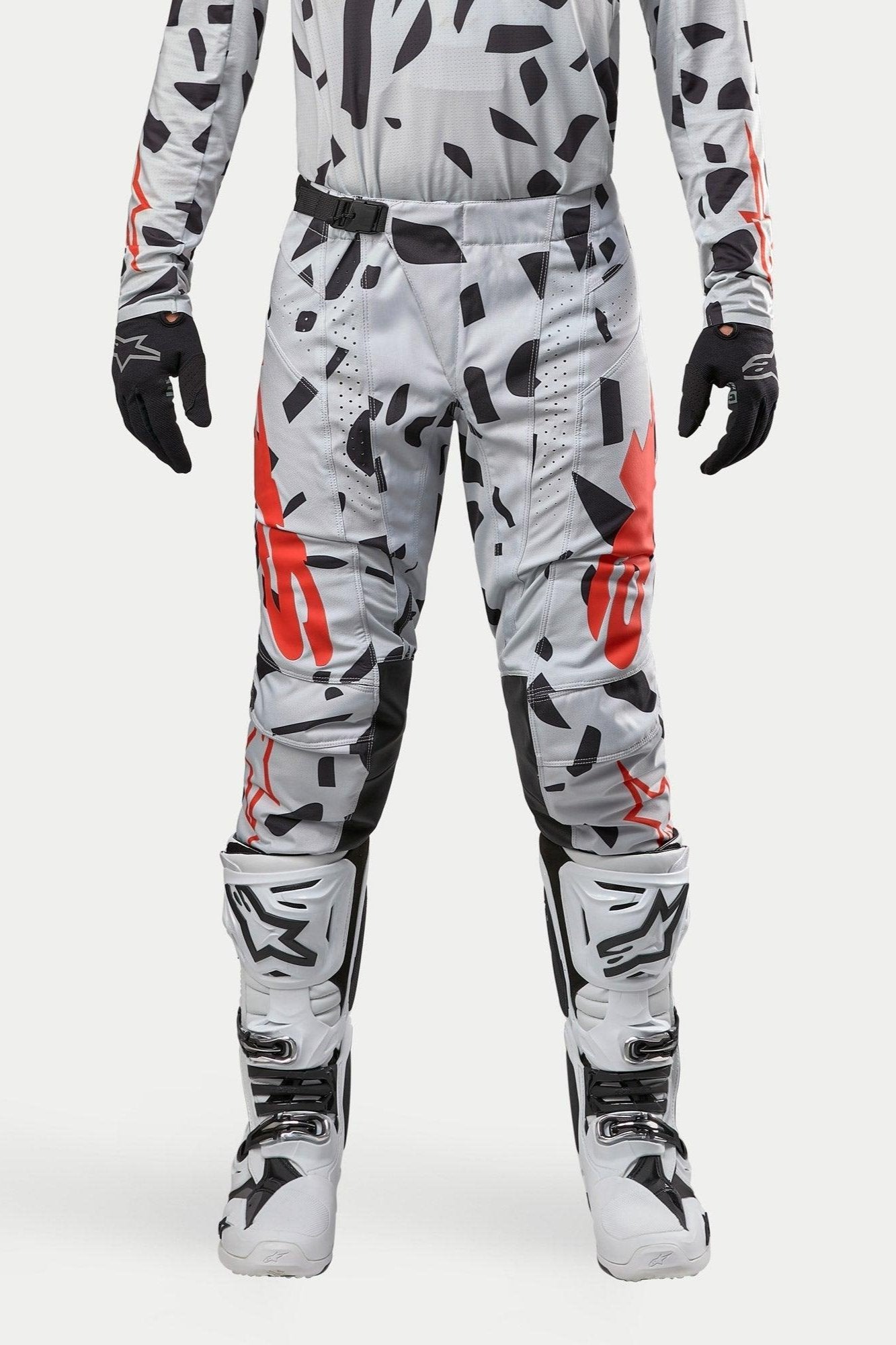 Spodnie Alpinestars Techstar Rantera 2024, spodnie motocrossowe, Haze Gray Camo, noszone z pasującą koszulką, czarnymi rękawicami i białymi butami, z czarnym wzorem w plamy i czerwonym brandingiem Alpinestars, wytrzymała konstrukcja do wyścigów off-road
