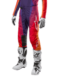 Alpinestars Techstar Pneuma Pants 2024, spodnie motocrossowe, fioletowe z pomarańczowymi, czerwonymi i niebieskimi akcentami, białe logo gwiazdy, białe buty i rękawice motocrossowe, sportowy krój