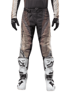 Alpinestars Techstar Pneuma Pants 2024, spodnie motocrossowe, kolor Dark Sand Iron Dust Gray, noszone z dopasowaną koszulką, czarnymi rękawicami i biało-czarnymi butami, klamra magnetyczna SX2, branding Astars, wytrzymała odzież off-road