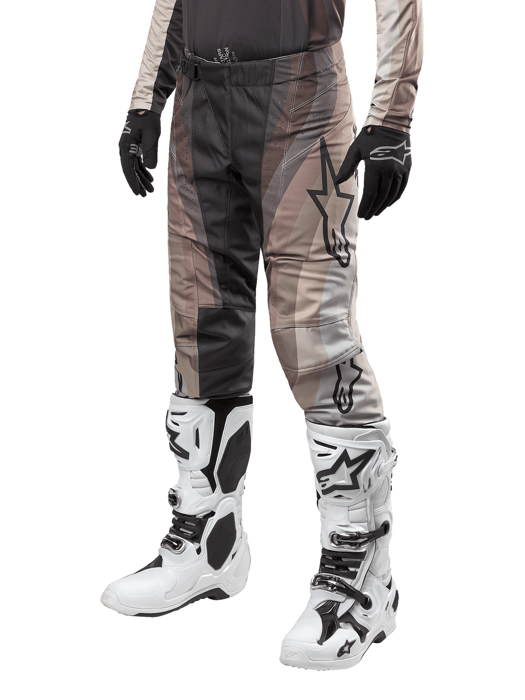 Spodnie Alpinestars Techstar Pneuma 2024, spodnie motocrossowe, w kolorach ciemnego piasku i szarym, noszone z biało-czarnymi butami i czarnymi rękawicami, z falistym wzorem i dużym logo gwiazdy, wytrzymała odzież do wyścigów terenowych