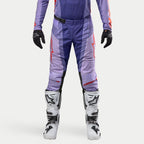 Alpinestars Techstar Ocuri Pants 2024, spodnie motocrossowe, fioletowe z jaskrawopomarańczowymi akcentami, sportowy krój wyścigowy, białe buty i czarne rękawice, laserowe perforacje dla lepszej wentylacji