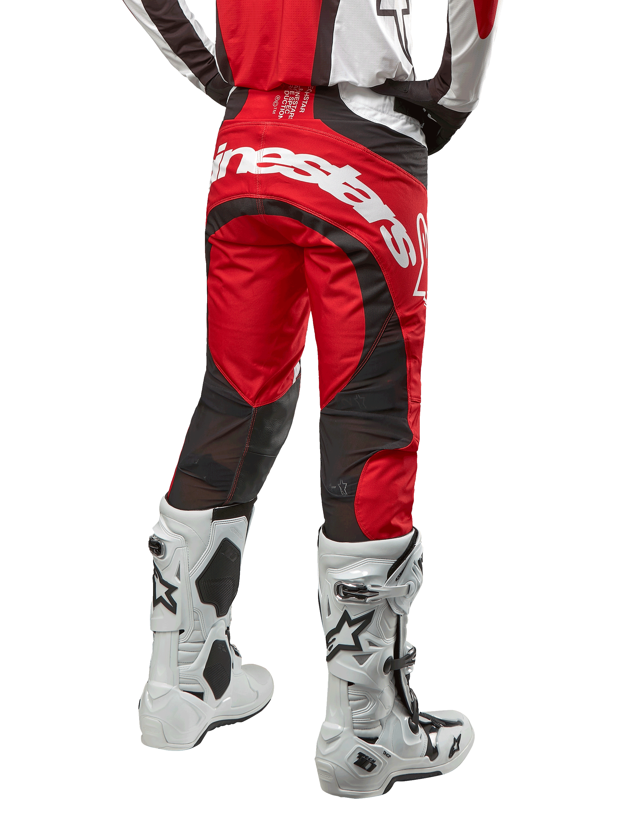 Alpinestars 2024 Techstar Ocuri Pants, spodnie motocrossowe, kolor Mars Red White and Black, widok z tyłu z dużym białym logo Alpinestars na siedzeniu, czarne siatkowe panele wentylacyjne, noszone z biało-czarnymi butami motocrossowymi, sportowy krój race-fit do jazdy terenowej
