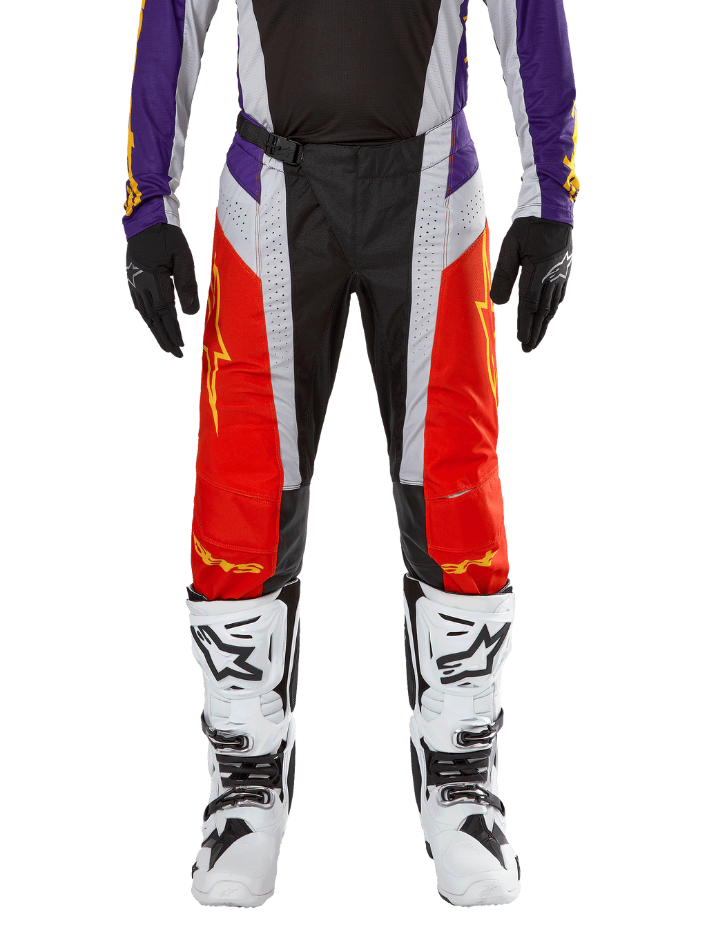 Spodnie Alpinestars Techstar Ocuri 2024, spodnie motocrossowe, jaskrawopomarańczowe, fioletowe i czarne, noszone z pasującą koszulką, czarnymi rękawicami i białymi butami, posiadają jaskrawopomarańczowe panele przednie, fioletowe akcenty w pasie i perforowane szare sekcje, techniczny design do wyścigów off-road