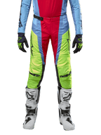 Alpinestars Techstar Ocuri Pants 2024, spodnie motocrossowe, jasnoniebieskie, neonowe żółte i czerwone, noszone z pasującą bluzą i białymi butami motocrossowymi, wyraziste panele kolorystyczne, czarne logo, wytrzymała konstrukcja o wyścigowym kroju