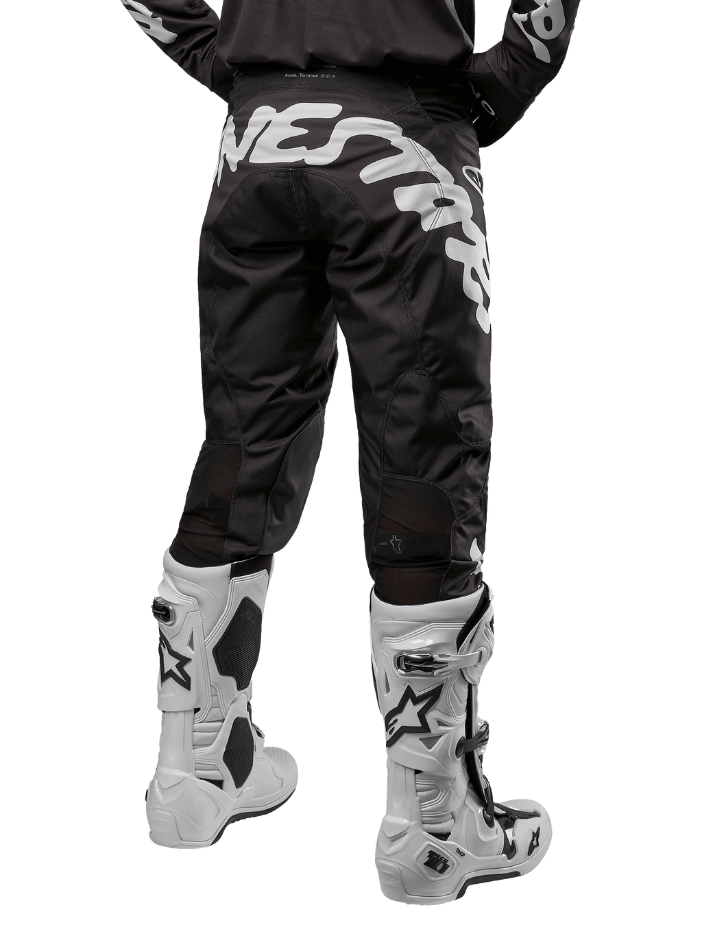Alpinestars Racer Hana Pants 2024, spodnie motocrossowe, czarne z dużym białym napisem Alpinestars z tyłu, białe buty off-road, widok od tyłu, sportowy design