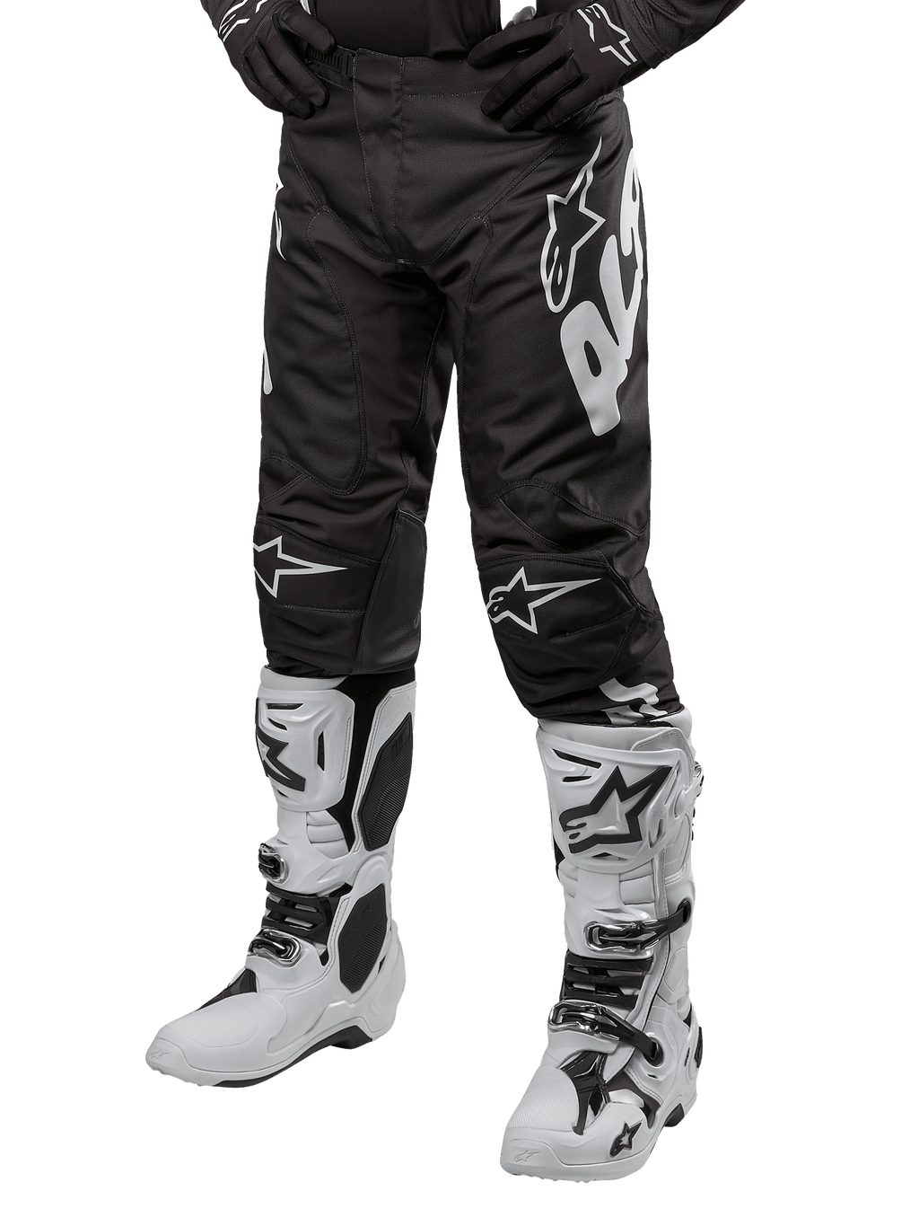 Alpinestars Racer Hana Pants 2024, spodnie motocrossowe, czarne z białymi akcentami i dużym logo, ergonomiczny sportowy design, widoczne białe buty motocrossowe, trwała konstrukcja do jazdy w terenie