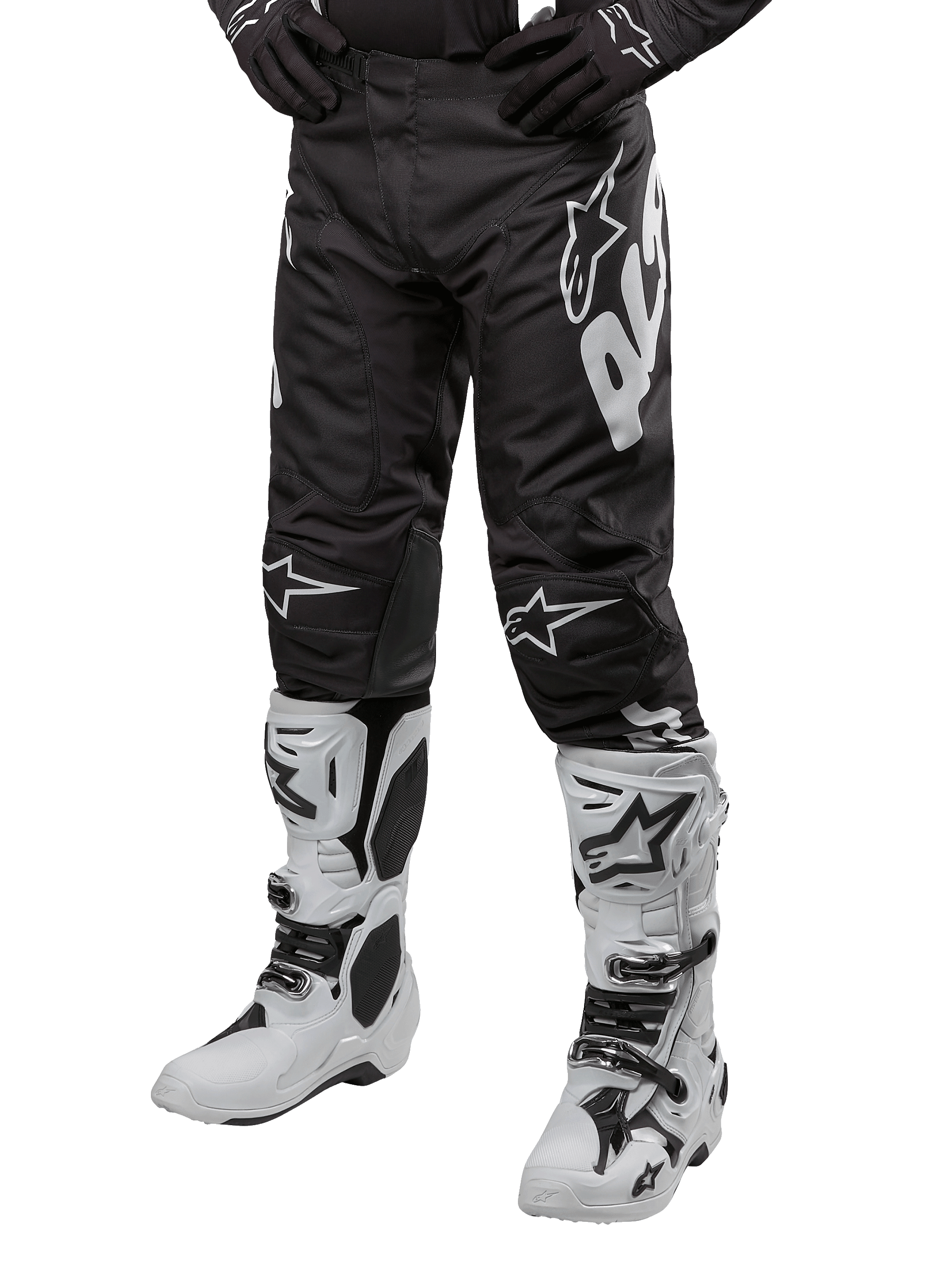 Alpinestars Racer Hana Pants 2024, spodnie motocrossowe, czarne z białymi akcentami i dużym logo, ergonomiczny sportowy design, widoczne białe buty motocrossowe, trwała konstrukcja do jazdy w terenie