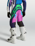 Spodnie Alpinestars Supertech Maven Młodzieżowe, niebieskie i różowe spodnie motocrossowe z neonowo zielonym logo, sportowy krój wyścigowy, widok z tyłu na modelu.