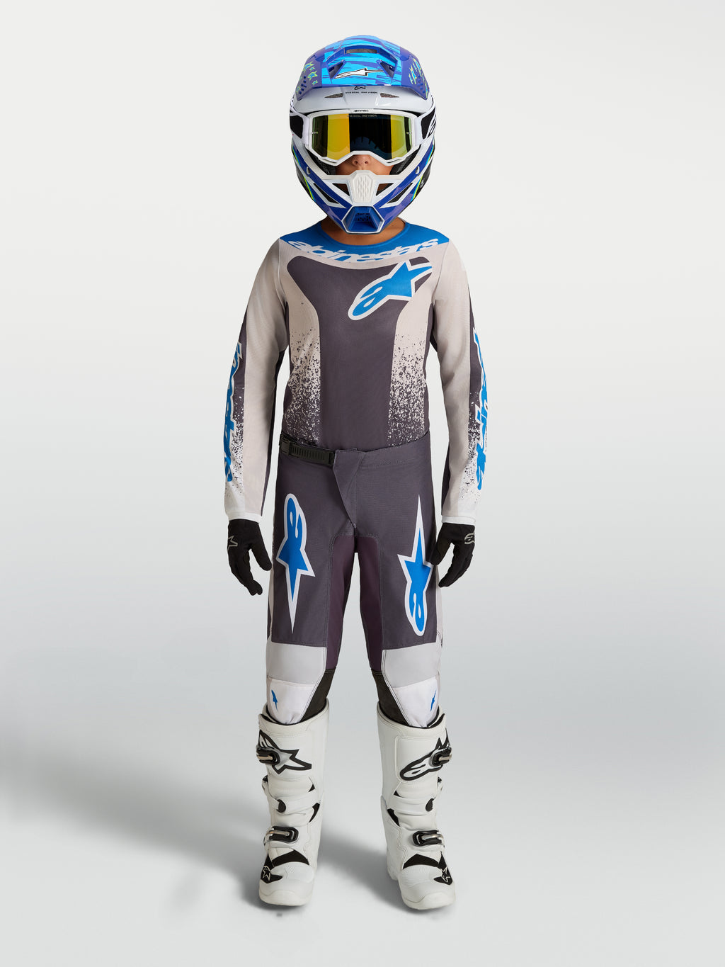 Spodnie Alpinestars Fluid Drag młodzieżowe, szaro-niebieska odzież motocrossowa z trwałego poliestru i białe buty.