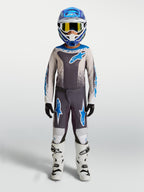 Spodnie Alpinestars Fluid Drag młodzieżowe, szaro-niebieska odzież motocrossowa z trwałego poliestru i białe buty.