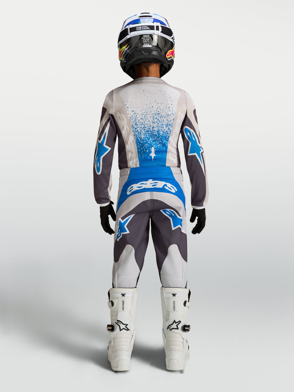 Alpinestars Fluid Drag, młodzieżowe spodnie motocrossowe, szare i niebieskie, widok od tyłu w kompletnym zestawie z koszulką i butami, wytrzymały sprzęt off-road