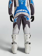 Alpinestars Spodnie Fluid Drag Młodzieżowe, niebieskie i szare spodnie motocrossowe, widok z tyłu z białą grafiką Astars.