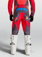 Alpinestars Spodnie Fluid Hunt młodzieżowe, czerwone i szare spodnie MX, widok z tyłu, niebieskie grafiki gwiazd.