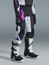 Alpinestars 2026 Youth Fluid Grid Pants, Motocross Pants, Black with white panels and vibrant pink and blue graphics, worn with matching black and white boots and black gloves, durable gear for youth off-road riding