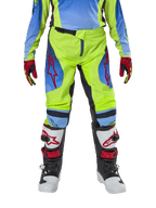 Młodzieżowe spodnie Alpinestars Racer Hoen 2024, spodnie motocrossowe, żółte neonowe i granatowe, z czerwonymi logotypami gwiazdy na udach, noszone z pasującą koszulką, czerwono-czarnymi rękawicami oraz biało-czarno-czerwonymi butami motocrossowymi, wytrzymały sprzęt do jazdy w terenie