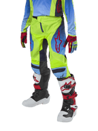 Alpinestars Youth 2024 Racer Hoen Pants, spodnie motocrossowe, żółte neonowe i granatowe z czerwonymi akcentami, zestawione z pasującymi rękawicami oraz białymi, czarnymi i czerwonymi butami, o sportowym kroju z profilowanymi nogawkami do wyścigów off-road