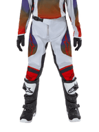 Alpinestars Youth 2024 Racer Hoen Pants, spodnie motocrossowe, jasnoszare, jaskrawopomarańczowe i czarne, zestawione z dopasowaną koszulką i czarno-białymi butami motocrossowymi, czerwone logo Alpinestars na udach i kolanach, sportowy design do wyścigów terenowych