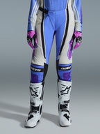 Alpinestars Stella Techstar Nomur 2026, damskie spodnie motocrossowe, jasnoniebieskie, w kolorze złamanej bieli i czarne, zestawione z białymi butami motocrossowymi i różowo-czarnymi rękawicami, z brandingiem „astars” na kolanach i techniczną wielopanelową konstrukcją dla kobiet