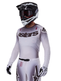 Koszulka Alpinestars Supertech Maker 2025, koszulka motocrossowa, srebrno-czarny gradient, oddychająca elastyczna siateczka z laserowo wycinanymi perforacjami, prezentowana z dopasowanymi spodniami i kaskiem, z logo „astars”, kompletny profesjonalny strój off-road