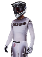 Koszulka Alpinestars Supertech Maker 2025, koszulka motocrossowa, srebrno-czarny gradient, oddychająca elastyczna siateczka z laserowo wycinanymi perforacjami, prezentowana z dopasowanymi spodniami i kaskiem, z logo „astars”, kompletny profesjonalny strój off-road