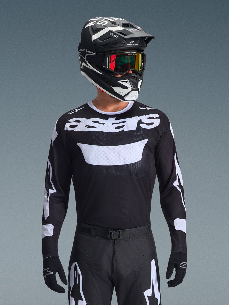 Alpinestars 2026 Racer Air Riway Jersey, Black and White motocross jersey with 'astars' branding, worn by a rider with matching black helmet, goggles, and pants, featuring breathable mesh panels for off-road racing.
