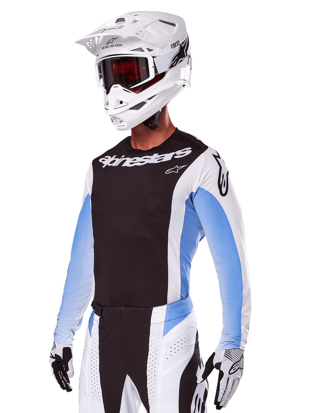 Motocyklista motocrossowy w zestawie Alpinestars 2025 Techstar Melt, biały z czarnymi i jasnoniebieskimi akcentami, koszulka z czarnym przodem i białymi rękawami, pasujące biało-czarne spodnie, biały kask SM10 z goglami i czarno-białe rękawice, kompletny profesjonalny strój wyścigowy off-road.