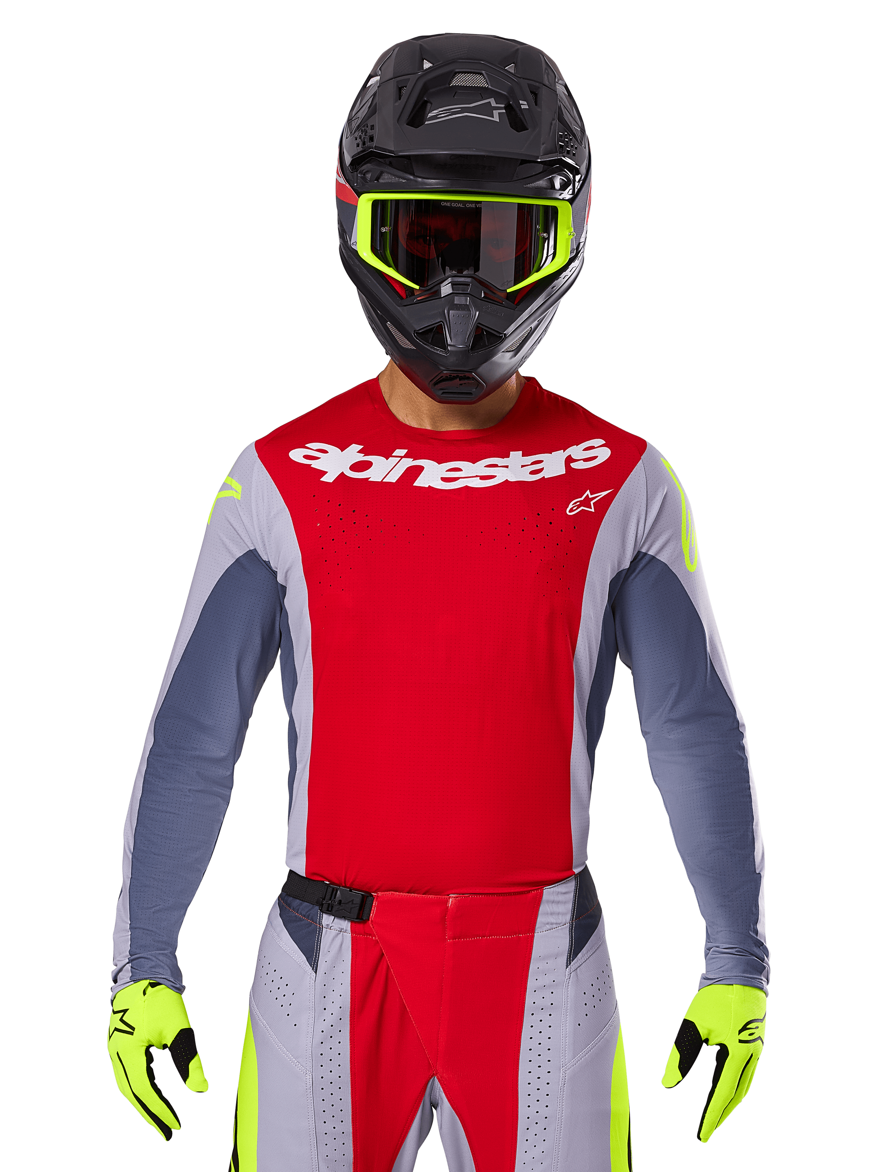 Motocrossista ubrany w koszulkę Techstar Melt 2025 i pasujące spodnie, jasnoczerwone i szare z białym brandingiem Alpinestars, czarny kask z neonowożółtymi goglami, pasujące neonowożółte rękawice, wentylowana odzież wyczynowa do wyścigów terenowych