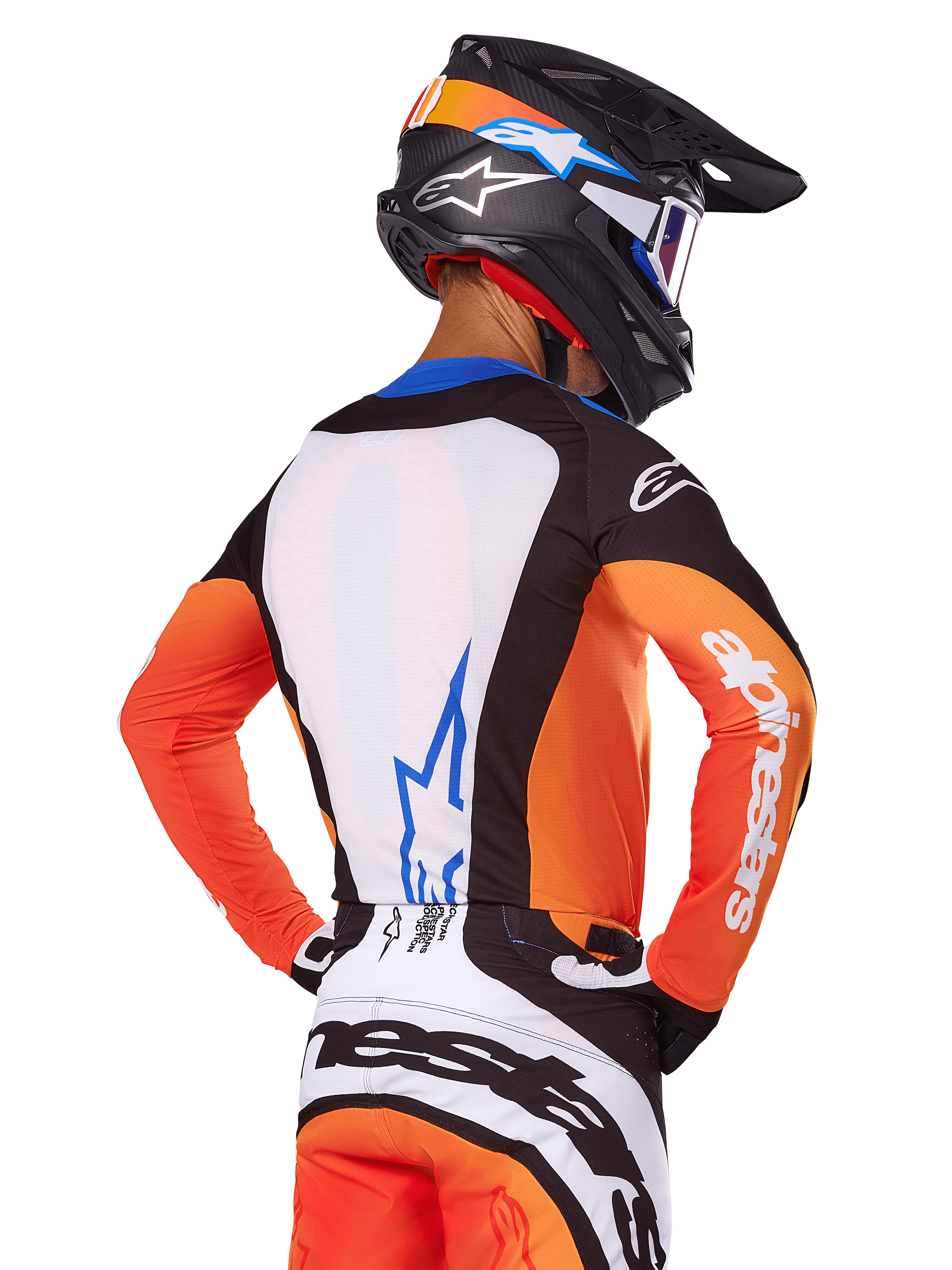 Zawodnik motocrossowy w koszulce Alpinestars Techstar Melt 2025, pomarańczowo-niebieska, widok z tyłu z białym panelem i niebieskim logo, pomarańczowe rękawy z białym brandingiem, kask i spodnie do kompletu, profesjonalny strój wyścigowy