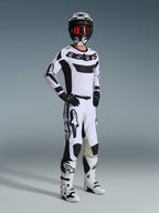 Motocyklista motocrossowy w pełnym stroju wyścigowym, koszulka Alpinestars 2026 Racer Riway w kolorze biało-czarnym, pasujące biało-czarne spodnie motocrossowe, czarny kask z lustrzanymi goglami, biało-czarne buty i czarne rękawice, skoordynowany zestaw do wyścigów terenowych