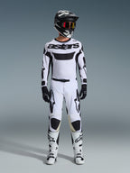 Koszulka Alpinestars 2026 Racer Riway, koszulka motocrossowa, biało-czarna, noszona jako kompletny zestaw wyścigowy z pasującymi spodniami, czarnym kaskiem z czerwonymi goglami, czarnymi rękawicami i białymi butami, z wyrazistym czarnym brandingiem „astars” i logo gwiazdy.
