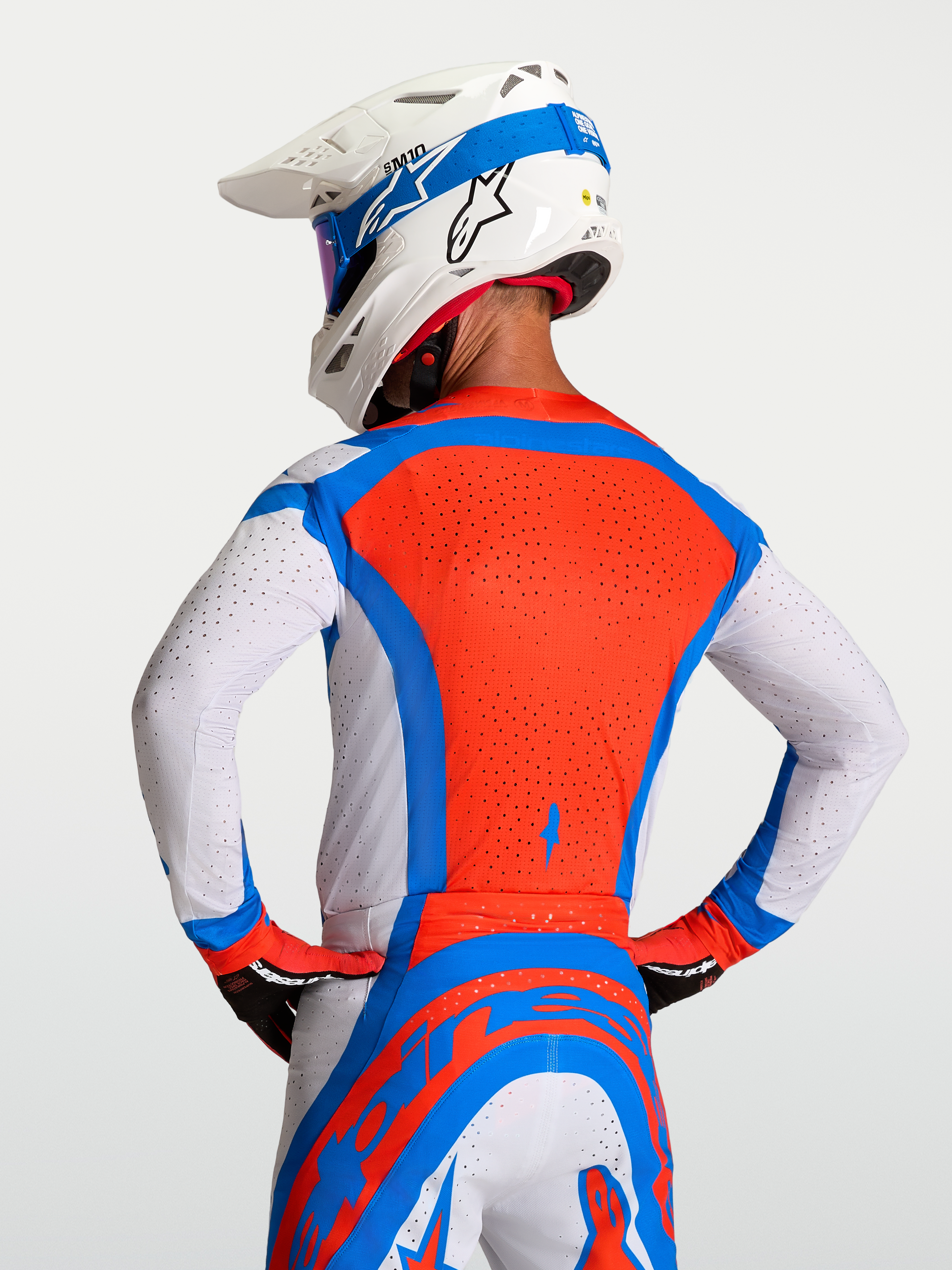 Koszulka Alpinestars Supertech Vesta, męska koszulka motocrossowa, czerwona, niebieska i biała, oddychające perforacje laserowe, widok z tyłu.