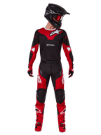 Zawodnik motocrossowy w zestawie Alpinestars Racer Veil 2025, czarno-czerwona koszulka z białym logo Alpinestars, pasujące spodnie motocrossowe, czarny kask z czerwonymi goglami, czerwone buty, kompletny zestaw wyczynowy do jazdy terenowej