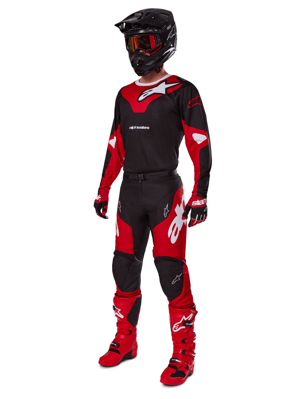 Zawodnik motocrossowy w kompletnym stroju wyścigowym Alpinestars 2025 Racer Veil w kolorze czarnym i jasnoczerwonym, pasujące spodnie, czerwone buty, czarny kask z czerwonymi goglami oraz czerwono-czarne rękawice, profesjonalny zestaw do wyścigów terenowych