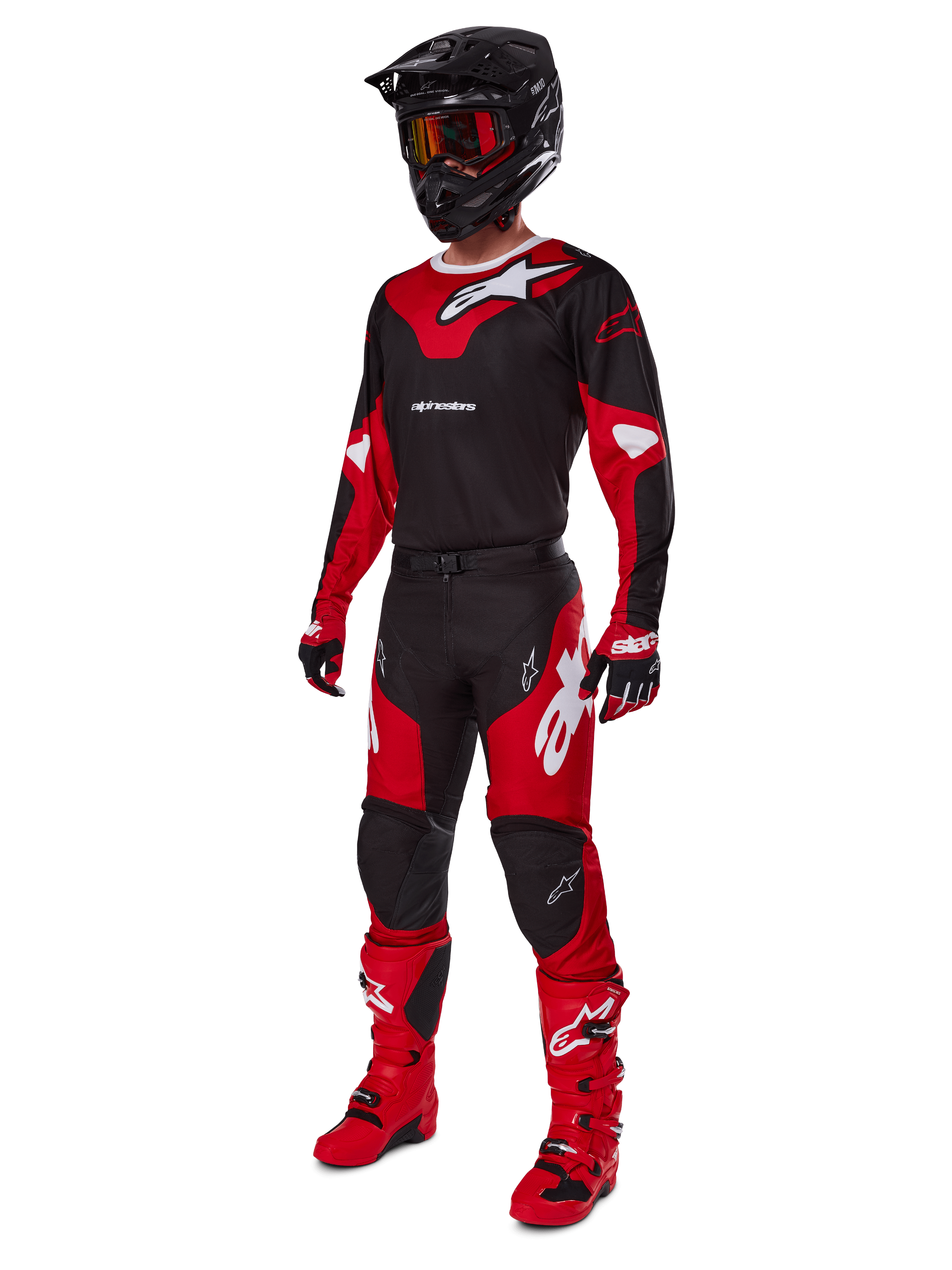 Zawodnik motocrossowy w kompletnym stroju wyścigowym Alpinestars 2025 Racer Veil w kolorze czarnym i jasnoczerwonym, pasujące spodnie, czerwone buty, czarny kask z czerwonymi goglami oraz czerwono-czarne rękawice, profesjonalny zestaw do wyścigów terenowych