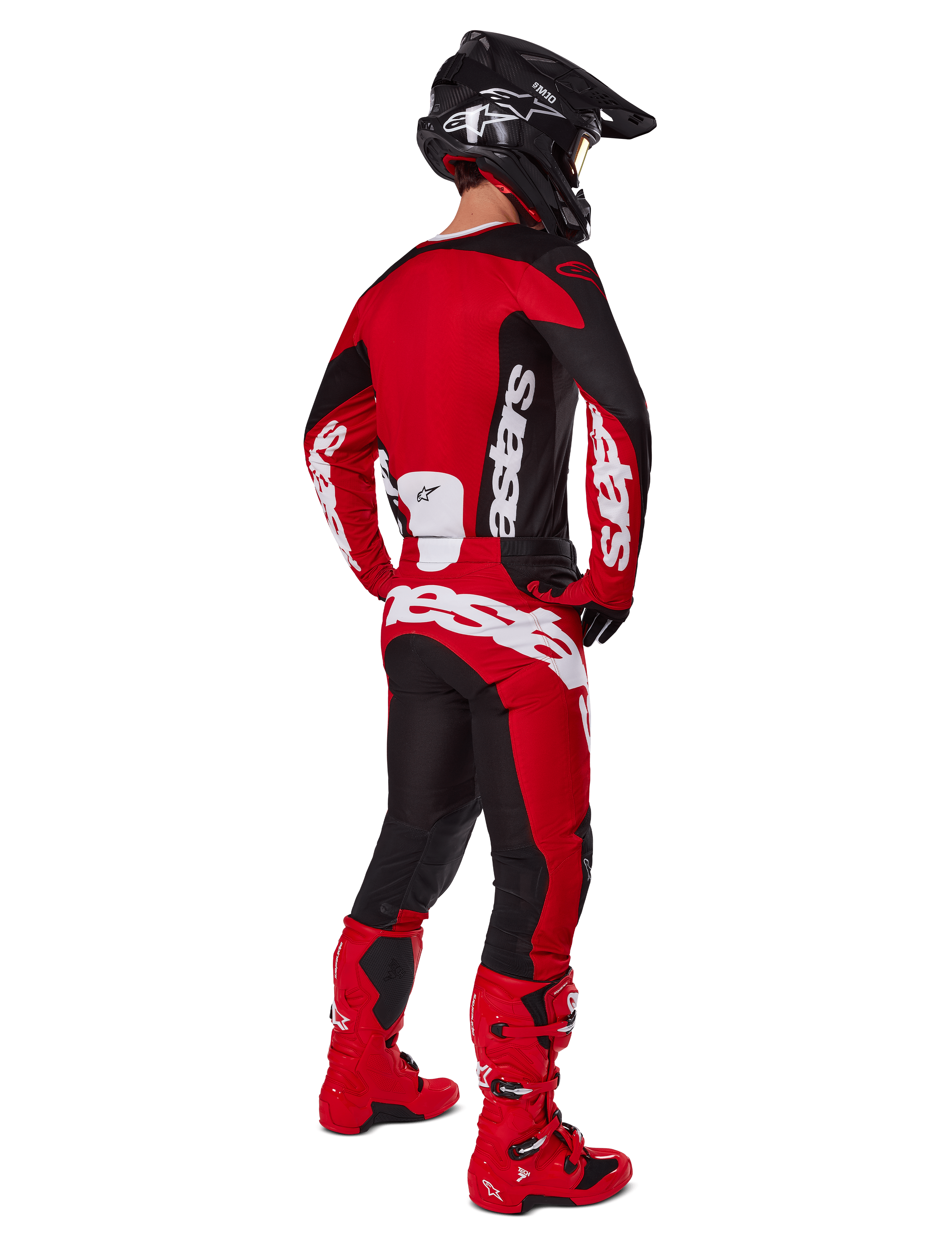 Motocyklista motocrossowy widoczny od tyłu, ubrany w koszulkę Alpinestars 2025 Racer Veil w kolorze czarnym i jaskrawoczerwonym, zestawioną z dopasowanymi czerwono-czarnymi spodniami i czerwonymi butami motocrossowymi, duże białe logo, idealna do jazdy terenowej