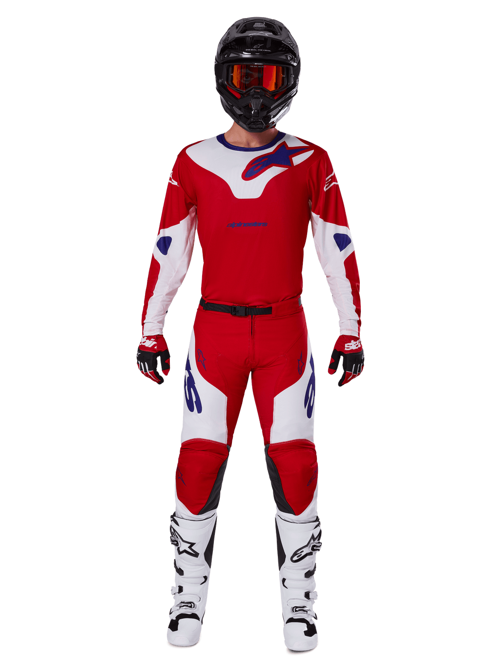 Zawodnik motocrossowy w zestawie Alpinestars 2025 Racer Veil, jaskrawoczerwona i biała koszulka oraz spodnie z niebieskimi akcentami, czarny kask z czerwonymi goglami, białe buty i czerwono-czarne rękawice, profesjonalny strój do jazdy terenowej
